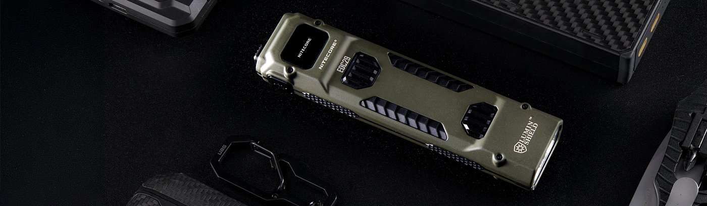 Nitecore EDC29 in Olive Drab surrounded by other everyday carry items like a power bank and ear buds.